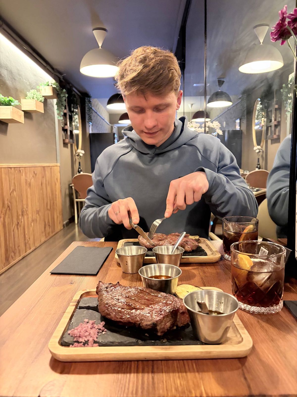Andy at a restaurant, cutting into a steak with a second full steak plate in front of him